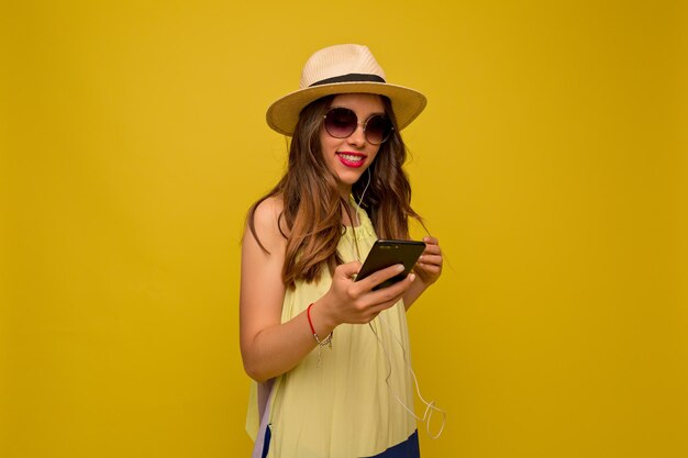 Primer plano retrato de niña feliz sonríe sobre piso amarillo Mujer de cabello castaño con vestido amarillo de verano y sombrero sonríe ampliamente con los dientes Buen humor concepto ocio