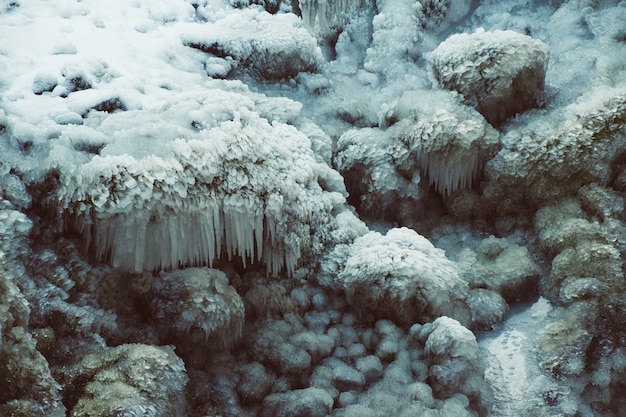 Primer plano de rocas cubiertas de nieve y hielo bajo la luz del sol en invierno