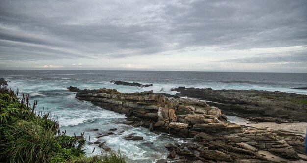 Primer plano de las rocas en una playa bajo un cielo lleno de nubes