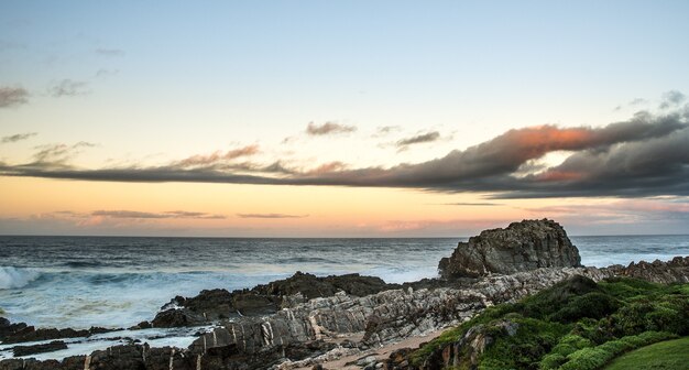 Primer plano de las rocas en una playa bajo un cielo lleno de nubes