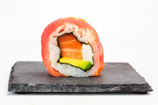 Primer plano de un rollo de sushi sobre una placa de piedra negra