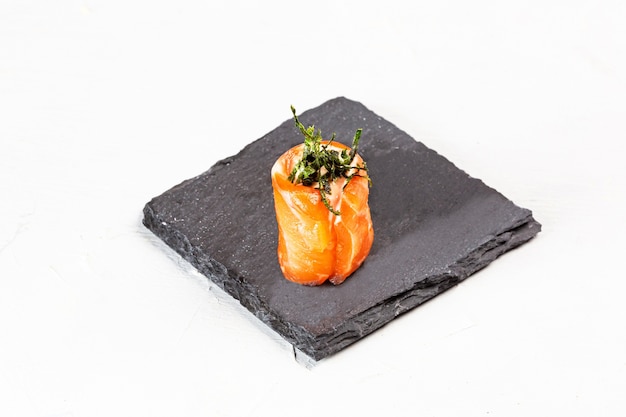 Primer plano de un rollo de sushi sobre una placa de piedra negra