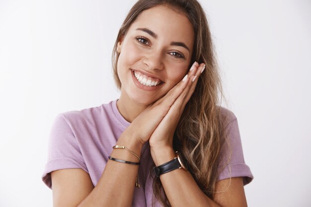 Primer plano romántico tonto lindo alegre mujer europea inclinada palmas de la cara sonriendo ampliamente sentirse feliz divertido, coqueteando riendo alegremente, teniendo una agradable conversación conmovedora, agradable charla