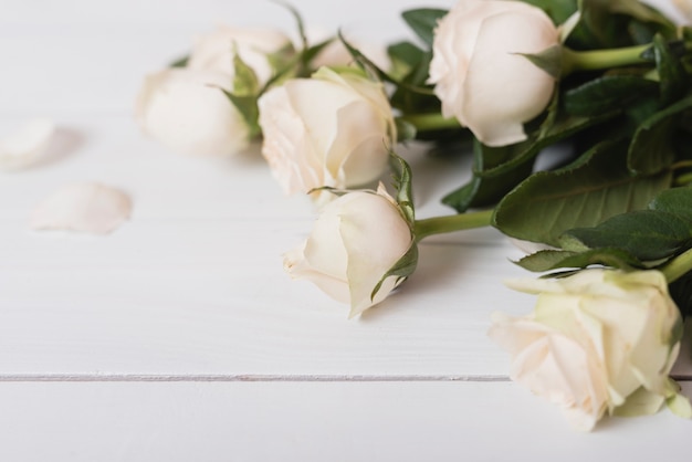 Primer plano de rosas blancas en mesa de madera