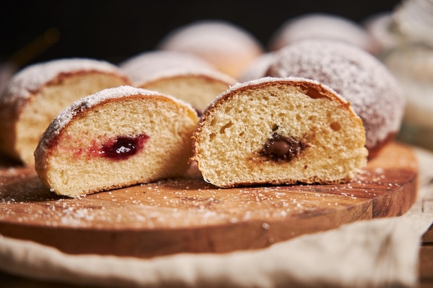 Primer plano de rosquillas cortadas esponjosas llenas de mermelada en una bandeja bajo las luces