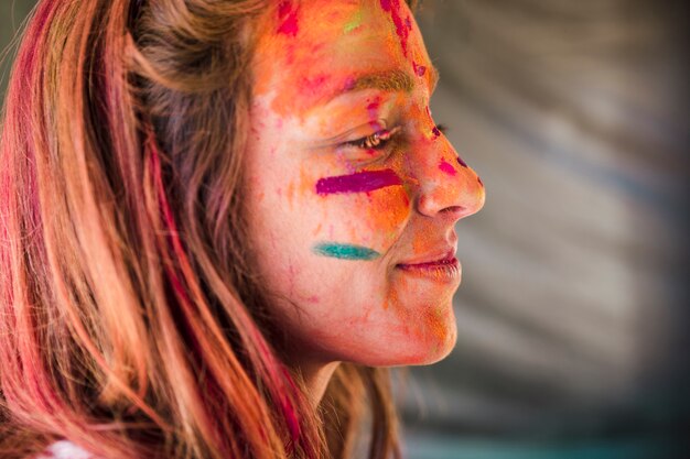 Primer plano del rostro de la mujer cubierto con holi color.