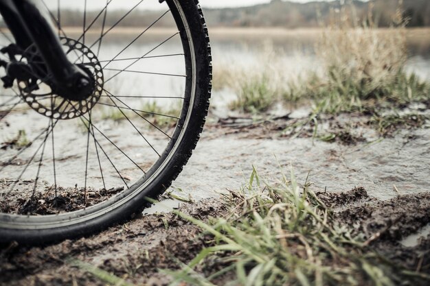 Primer plano de rueda de bicicleta de montaña en el barro cerca del lago