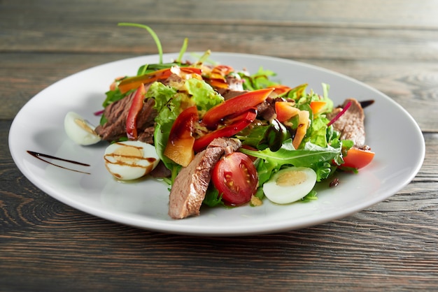 Primer plano de sabrosa ensalada fresca con carne a la parrilla y huevos y salsa verde pimienta delicioso comer nutrición saludable almuerzo cena cena cocina cocina ingredientes receta.