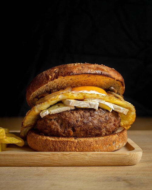 Primer plano de sabrosa hamburguesa de ternera casera fresca y patatas fritas en una bandeja de madera