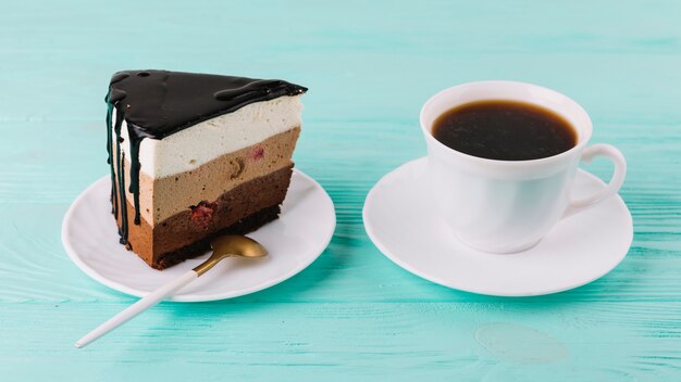 Primer plano de un sabroso pastel cremoso con una cuchara y una taza de té