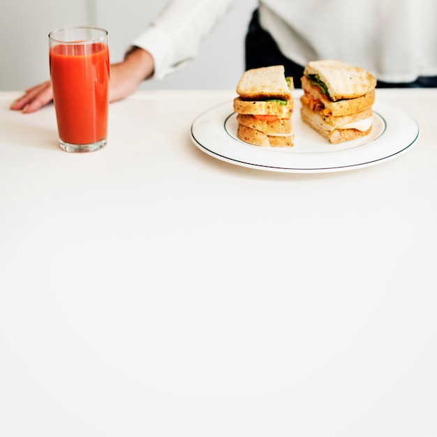 Primer plano de sandwich y jugo en la mesa blanca