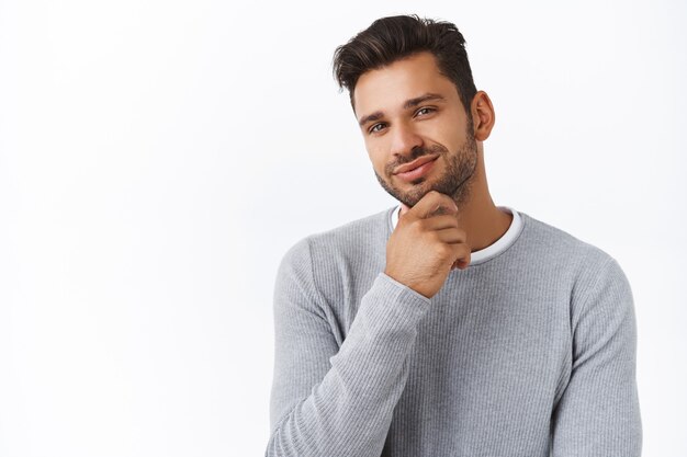 Primer plano satisfecho guapo chico barbudo hizo su elección, orgulloso o complacido con una buena decisión, frotando la barbilla sonriendo en aprobación, expresión de acuerdo, como idea de qué comprar novia para regalo de cumpleaños