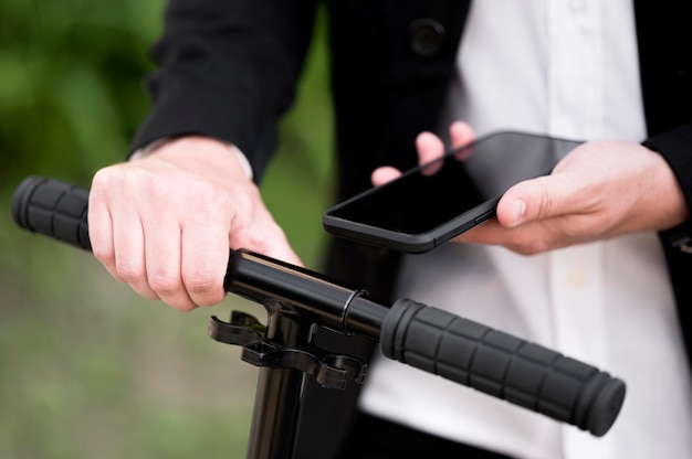 Primer plano scooter de desbloqueo masculino con teléfono móvil