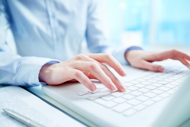 Primer plano de secretaria escribiendo en el teclado