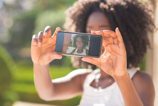 Primer plano de la señora negra Taking Selfie foto en el parque