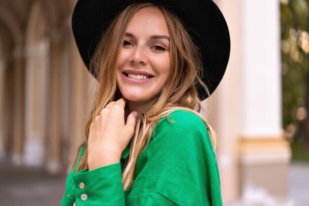 Primer plano sensual retrato de mujer rubia elegante con maquillaje natural de pelos rizados y cara bonita, con sombrero negro