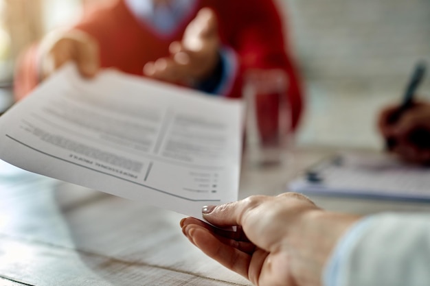 Foto gratuita primer plano de un solicitante de empleo dando su currículum durante una entrevista de trabajo en la oficina