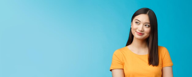 Primer plano soñador esperanzado encantador joven mujer asiática usar camiseta amarilla girar hacia los lados sonriendo encantado