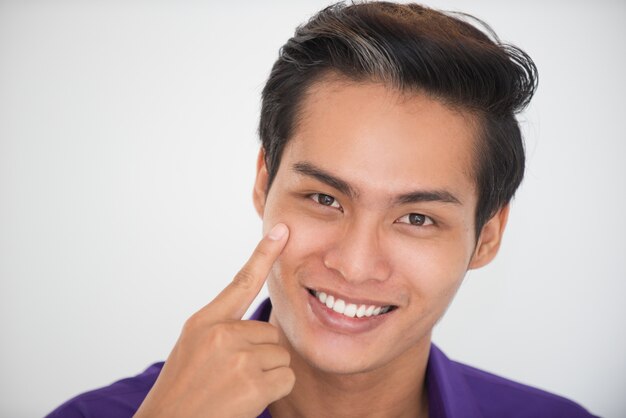 Primer plano de sonriente asiático tocar la mejilla