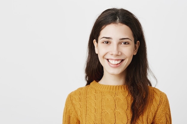 Primer plano de la sonriente cara de niña morena, mujer atractiva esperanzada