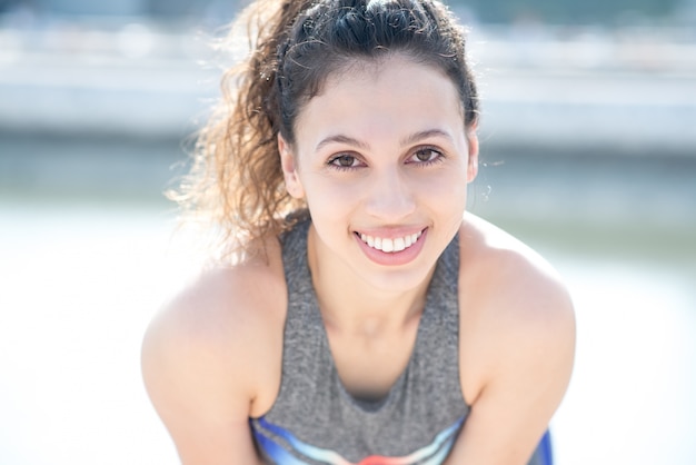 Primer plano de sonriente deportiva atractiva chica al aire libre