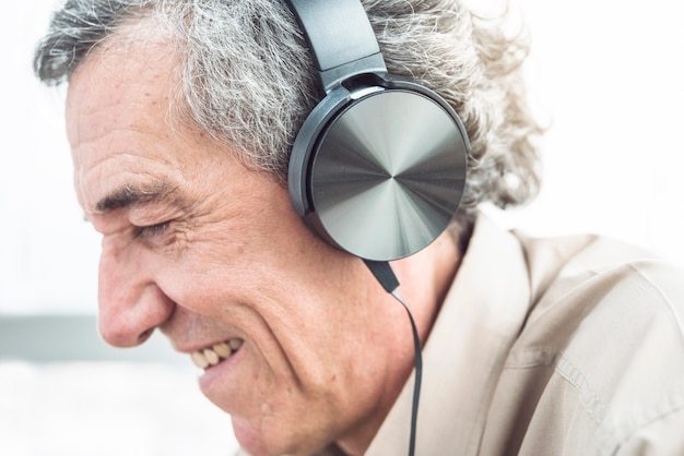 Primer plano de sonriente hombre senior disfrutando de la música en auriculares