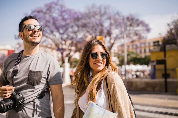 Primer plano de sonriente joven pareja de turistas de pie en la calle