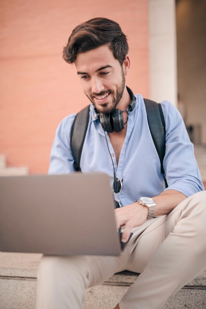 Primer plano de un sonriente joven usando laptop