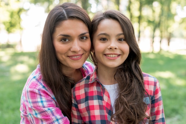 Foto gratuita primer plano de sonriente madre e hija de pie juntos en el parque