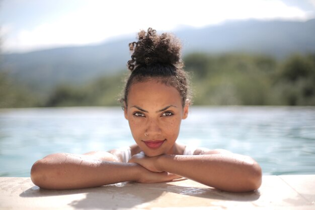 Primer plano de una sonriente mujer de pelo negro en la piscina