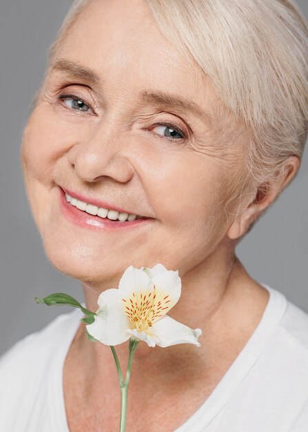 Primer plano sonriente mujer sosteniendo flor