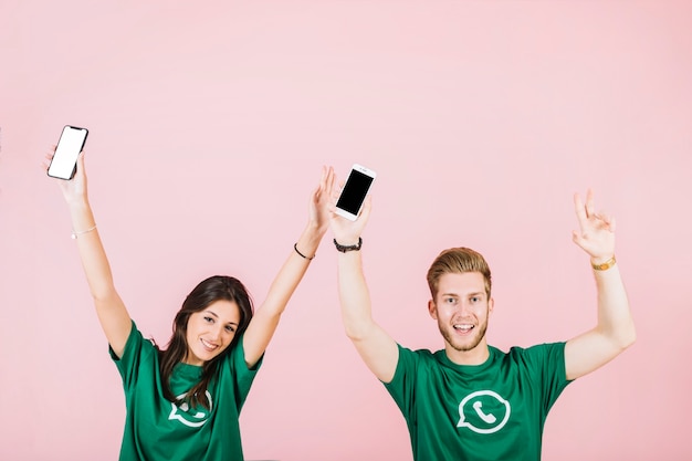 Foto gratuita primer plano de sonrientes hombre y mujer con teléfono móvil alzando sus brazos