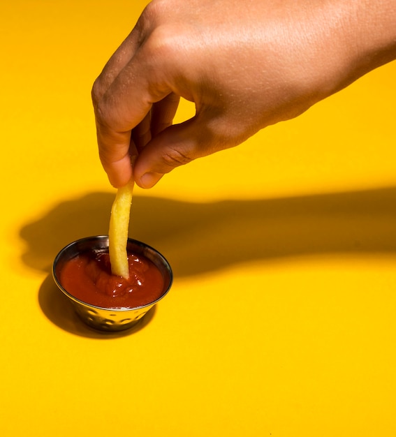 Primer plano sumergir las papas fritas en salsa de tomate