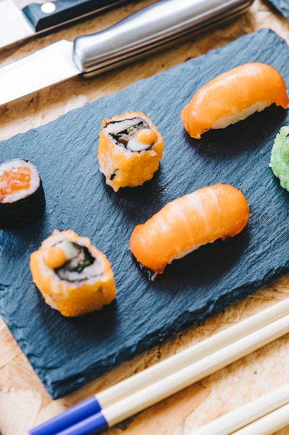 Primer plano de sushi cerca de los palillos y cuchillo