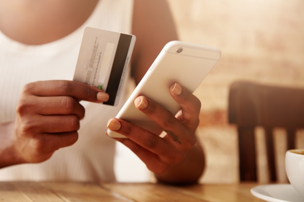 Primer plano de una tarjeta de crédito y un teléfono inteligente en manos de mujer