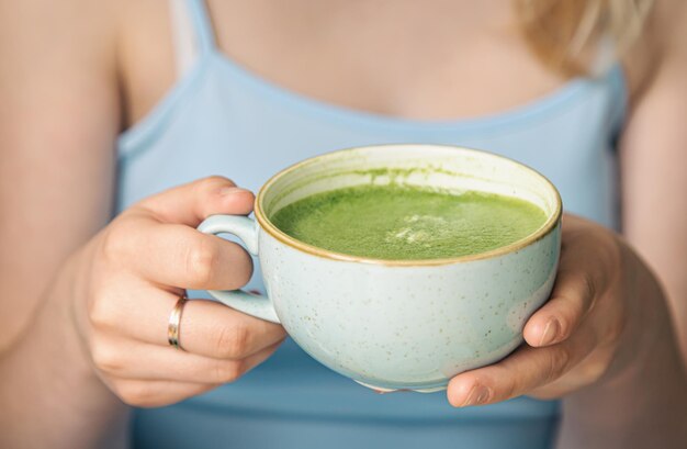 Primer plano de una taza con bebida de matcha verde en manos femeninas