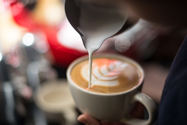 Primer plano de taza de café con una flor de espuma