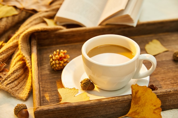 Primer plano de una taza de café y hojas de otoño sobre la superficie de madera