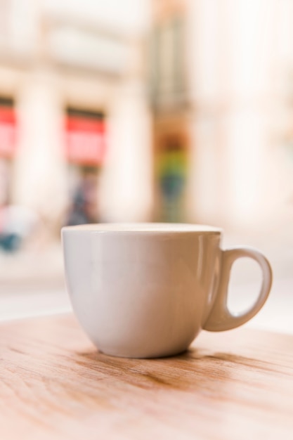 Primer plano de una taza de café con leche en la mesa de madera