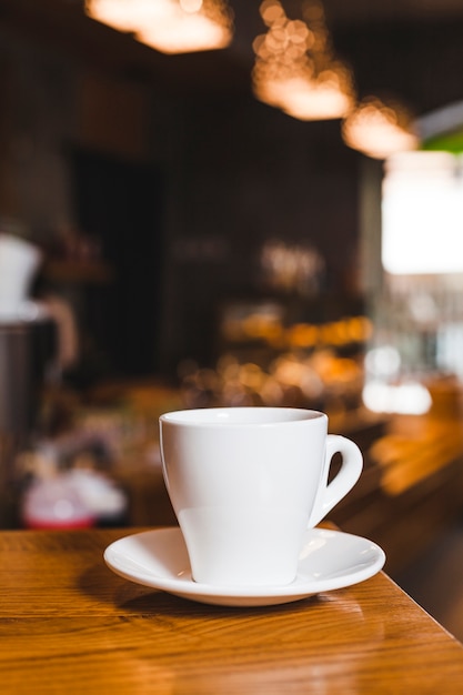 Primer plano de la taza de café en la mesa de madera en la cafetería