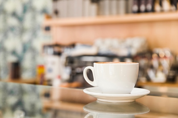 Primer plano de la taza de café en el mostrador de vidrio