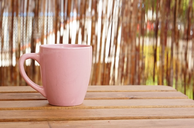 Primer plano de una taza rosa sobre una mesa de madera