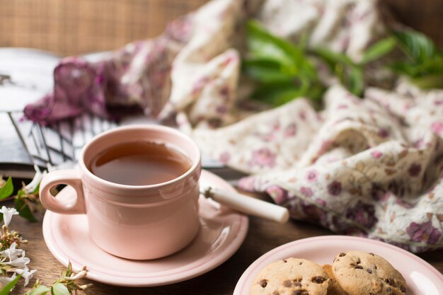 Primer plano de la taza de té de hierbas y galletas en la mesa