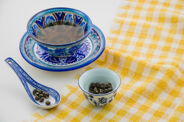 Primer plano de la taza de té oolong con una cuchara en el mantel contra el fondo blanco