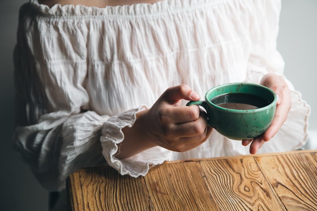 Primer plano taza verde con café en manos femeninas