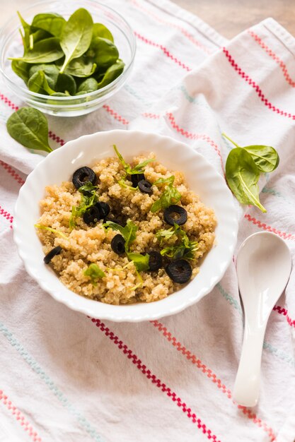 Primer plano de un tazón de avena saludable adornado con hojas de albahaca y oliva para el desayuno