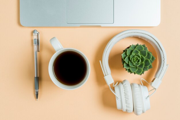 Primer plano de té y auriculares cerca de la computadora portátil