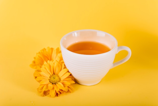 Primer plano de té y flores sobre fondo amarillo