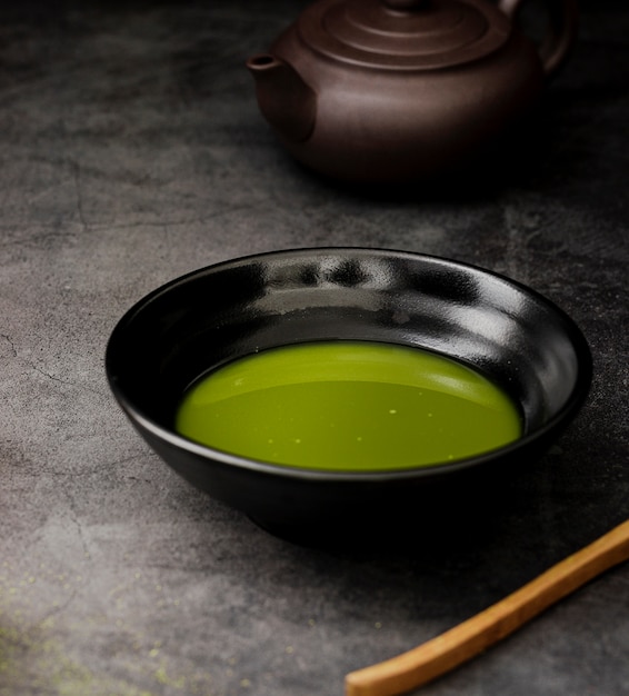 Primer plano de té matcha en un tazón con tetera