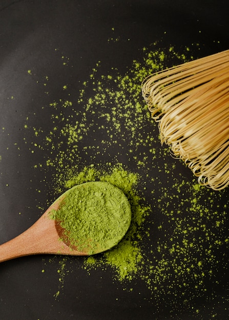 Primer plano de té en polvo matcha en cuchara de madera con batidor de bambú